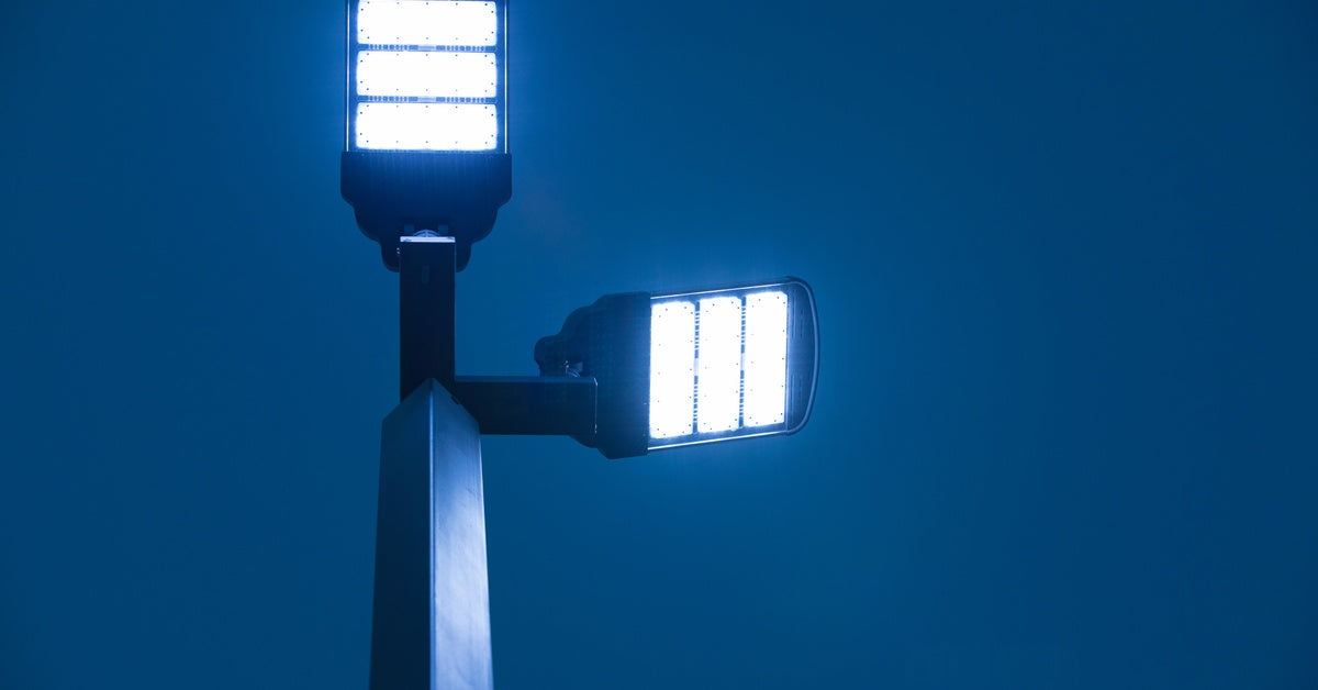 An LED solar street lamp shines bright against a nighttime background. The sky looks blue in the darkness.